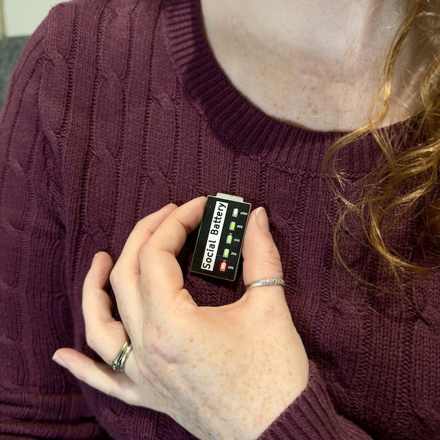 person wearing a social battery pin badge